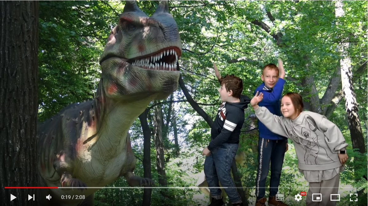 Trójka dzieci stoi obok dinozaura na planie filmowym