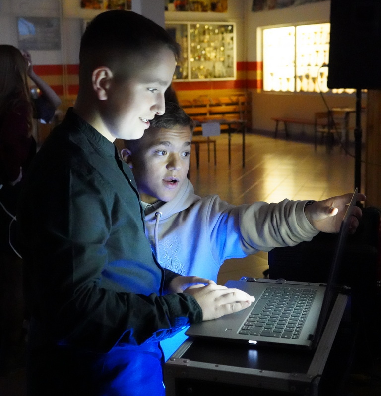 Dwóch chłopców obsługuje laptopa na dyskotece szkolnej