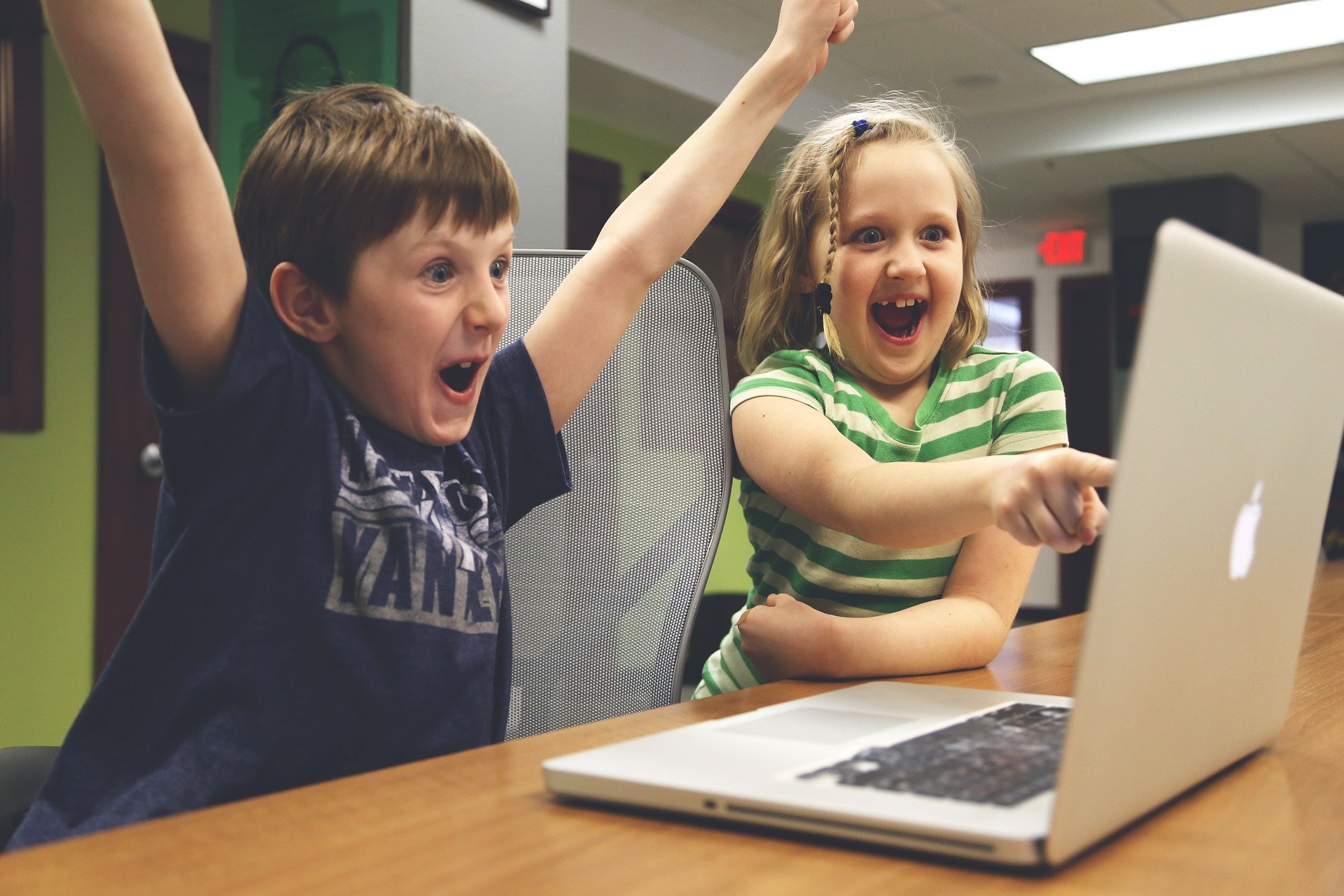 Dzieci siedzą przed komputerem i cieszą się z wygranej